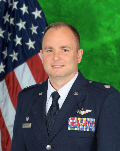 Lt Col Matthew Campise posing in front of green background and U.S. flag. 
