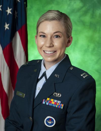 Captain Sarah Garvin posing in front of green background and U.S. flag. 
